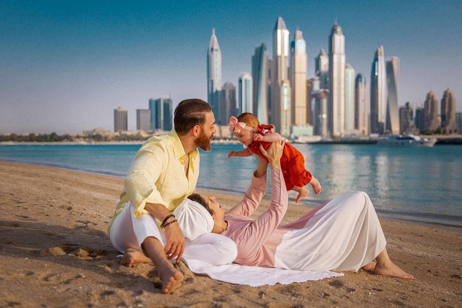 A family on the beach with the Dubai Marina skyline behind them